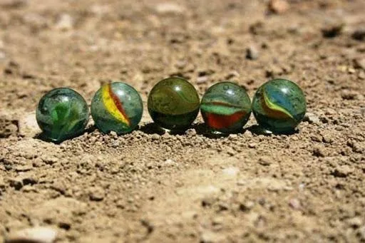 Toprak zeminde yan yana dizilmiş renkli misketler